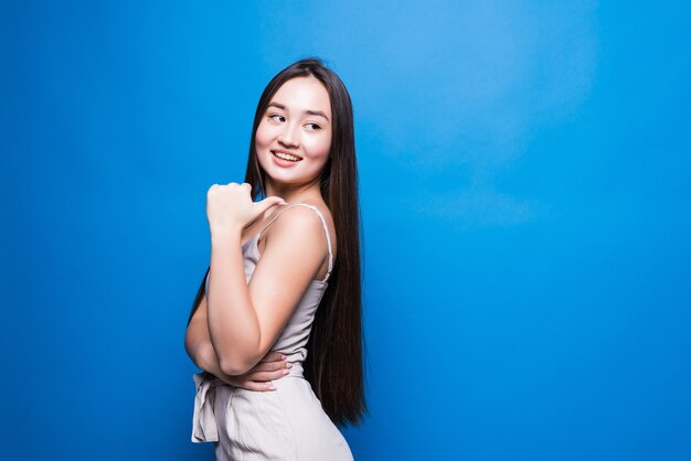 Young beautiful asian woman pointing to the back behind with hand and thumbs up, smiling confident