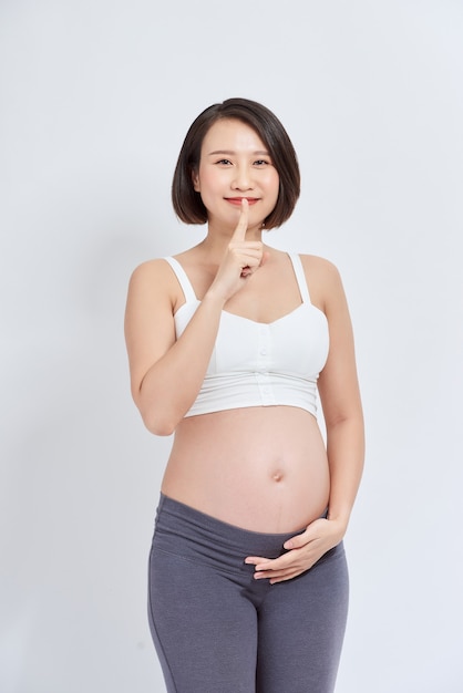 젊은 아름다운 아시아 여성 임신한 아기가 입술에 손가락을 대고 조용히 해달라고 요청합니다. 침묵과 비밀 개념.