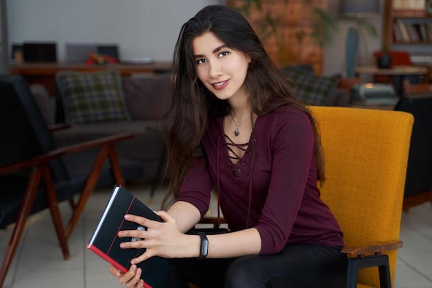 Young beautiful Asian woman reading book in a cafe