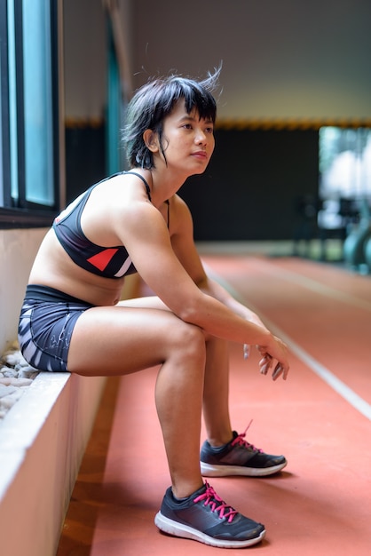 사진 젊은 아름 다운 아시아 여자 앉아서 체육관에서 휴식