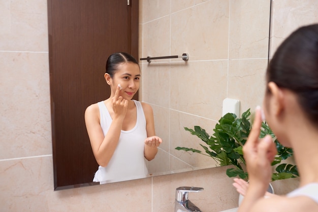 Young beautiful asian woman washing her face with hands by soap