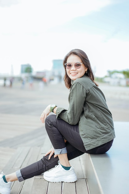 Young Beautiful Asian Woman Wearing Jacket And Black Jeans Posing Outdoors