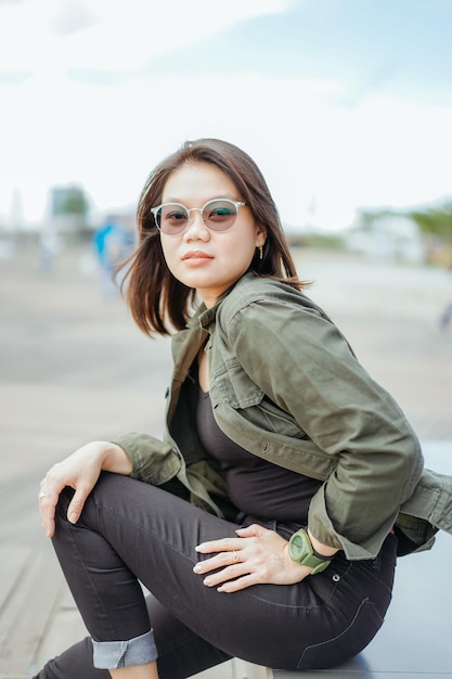 Young Beautiful Asian Woman Wearing Jacket And Black Jeans Posing Outdoors