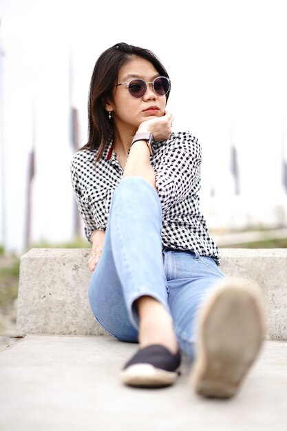 Young Beautiful Asian Woman Wearing Plaid Shirt And Blue Jeans Posing Outdoors