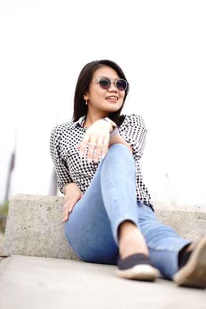 Young Beautiful Asian Woman Wearing Plaid Shirt And Blue Jeans Posing Outdoors