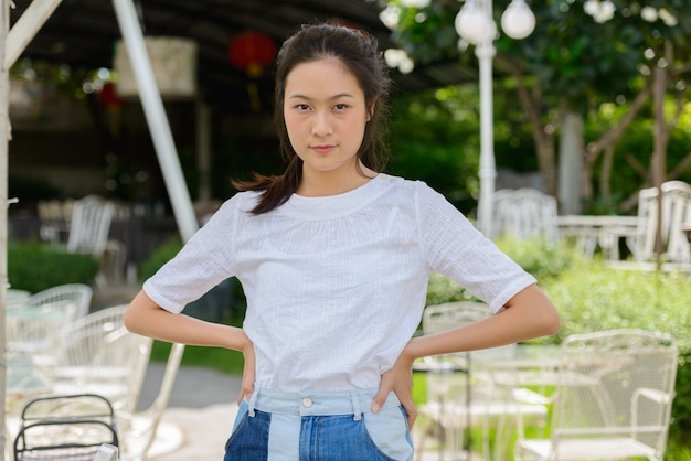 Young beautiful Asian woman with arms crossed at the coffee shop outdoors