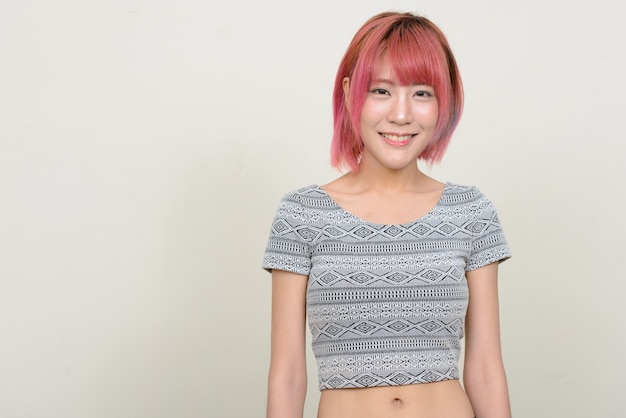 Photo young beautiful asian woman with pink hair against white wall