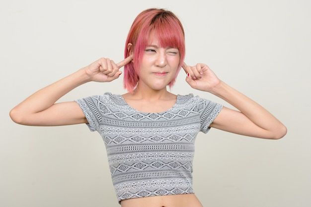  young beautiful Asian woman with pink hair against white wall