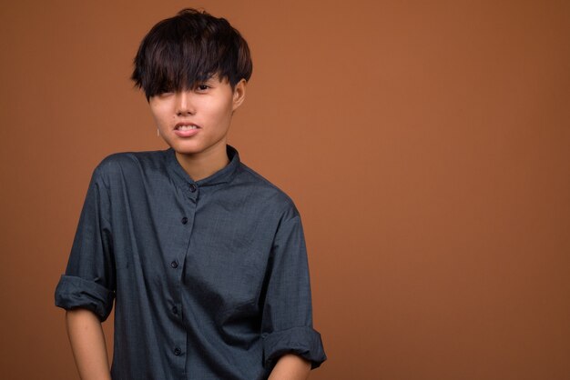 Young beautiful Asian woman with short hair against brown