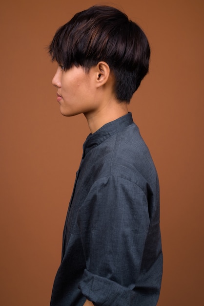 Young beautiful Asian woman with short hair against brown