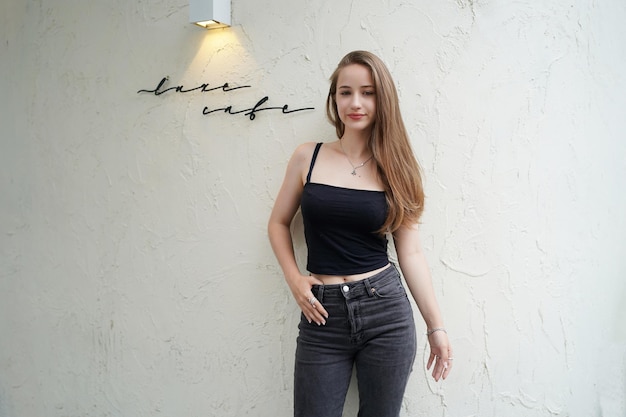 Photo young beautiful and attractive woman with long brown hair in a black dress at cafe against urban background.