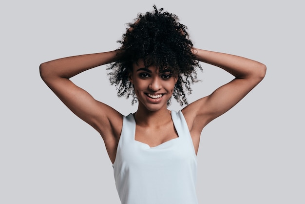 young and beautiful. attractive young african woman in casual wear keeping hands in hair and smiling