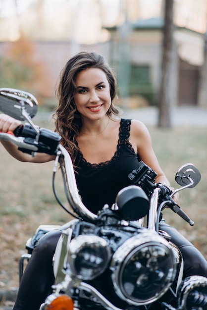 Young beautiful biker girl in a black tank top and leather pants on a motorcycle. The concept of speed and freedom