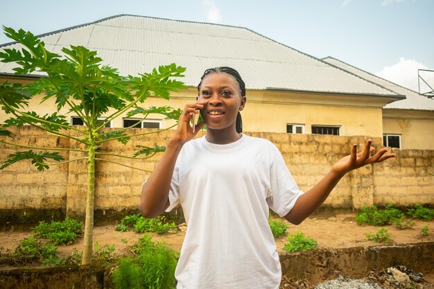 Photo young beautiful black lady holding her smartphone to make a phone call smiling