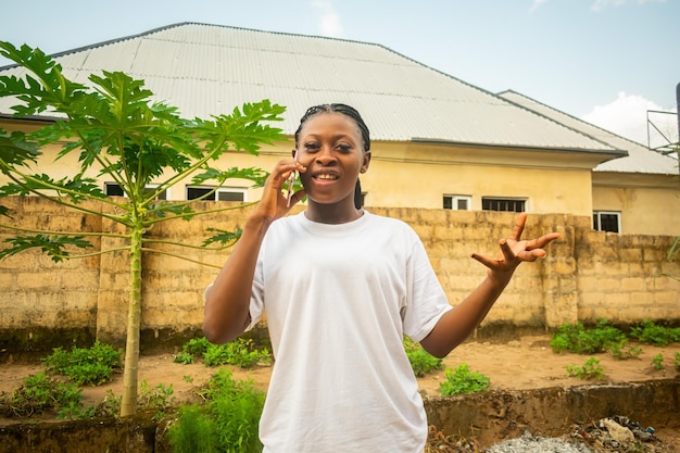 Photo young beautiful black lady holding her smartphone to make a phone call smiling