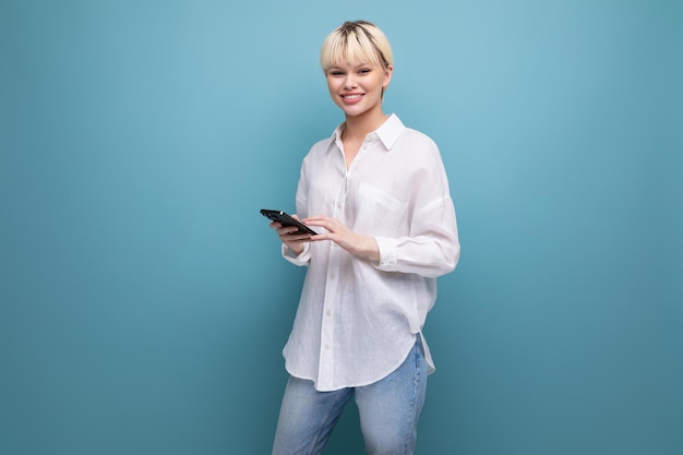 Young beautiful blond office worker woman with a bob hairstyle and dressed in a white shirt uses a