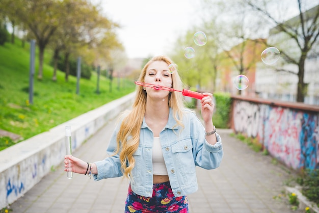 Young beautiful blonde caucasian girl playing with bubble soap