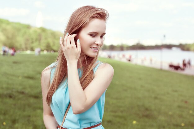 青いドレスを着た若い美しいブロンドの女の子。公園で春の散歩。細くて柔らかい。健康的な生活様式。