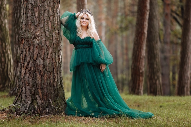 Young beautiful blonde hair woman queen. Princess walks. autumn green forest mystic. Vintage medieval shiny crown.