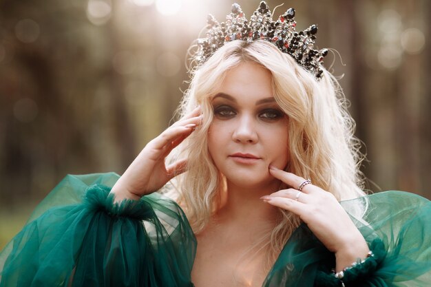 Young beautiful blonde hair woman queen. Princess walks. autumn green forest mystic. Vintage medieval shiny crown.