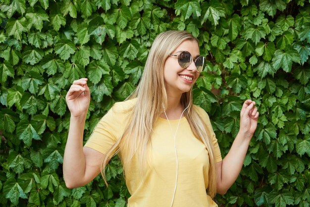 Young beautiful blonde listens to music using headphones in a mobile phone rejoices dances