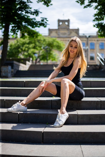 Young beautiful blonde sportive woman in a black tank top and in black tight 