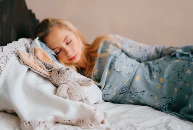 Young beautiful blonde teen sleeping on vintage wooden bed. 