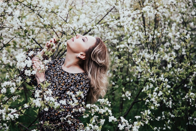 Young beautiful blonde woman in blooming garden.