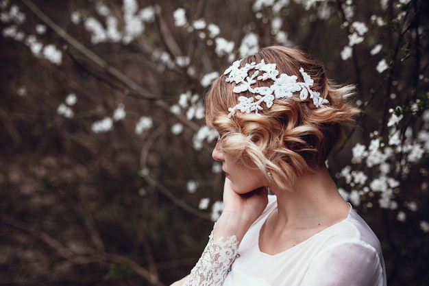 Young beautiful blonde woman in blooming garden.