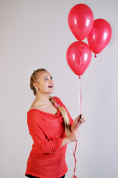 Young beautiful blonde woman holding three balloons