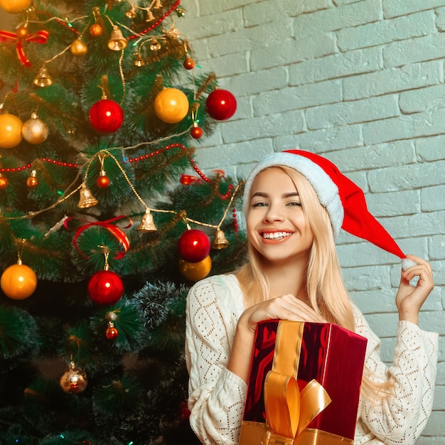 Молодая красивая блондинка женщина возле елки с подарком. Рождественское настроение. Новый год.