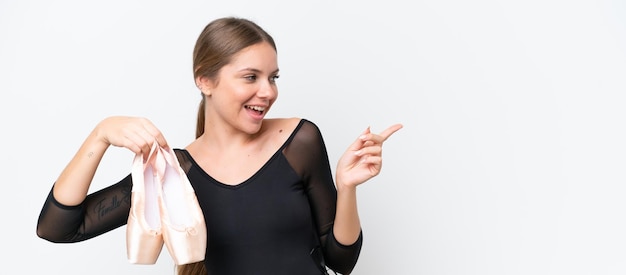 Young beautiful blonde woman practicing ballet isolated on white background pointing finger to the side and presenting a product