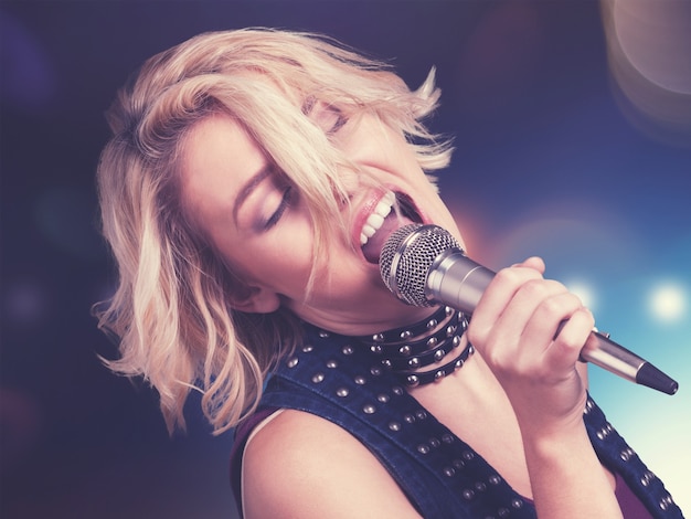 Young beautiful blonde woman sing song with microphone