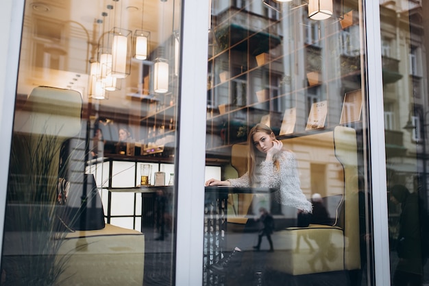 Young beautiful blonde woman sitting in a cafe in the city center