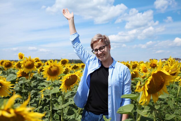 Giovane bella donna bionda in piedi nel campo di girasoli