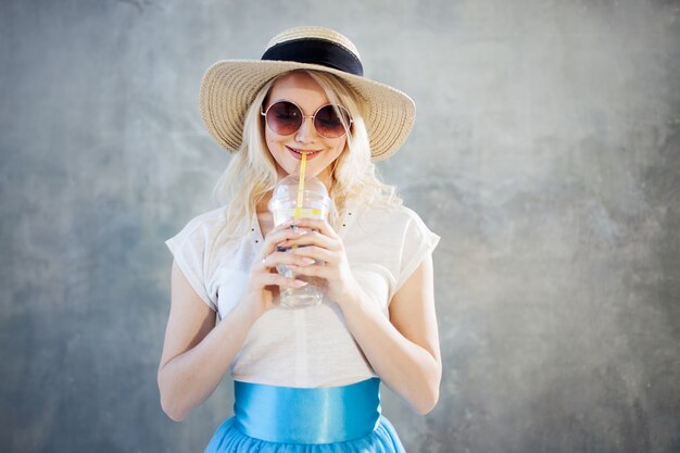 麦わら帽子の若い美しいブロンドの女性。夏スタイルのサングラス。