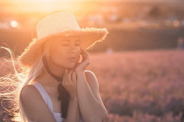 Foto giovane bella donna bionda che indossa cappello di paglia nel prato sopra la natura