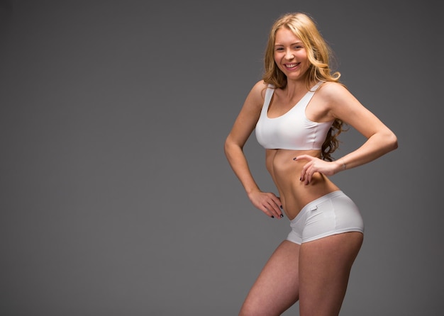 Photo young beautiful blonde woman in white fitness clothing dark gray isolated background