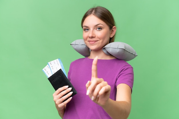 Young beautiful blonde woman with Inflatable travel Pillow over isolated background showing and lifting a finger