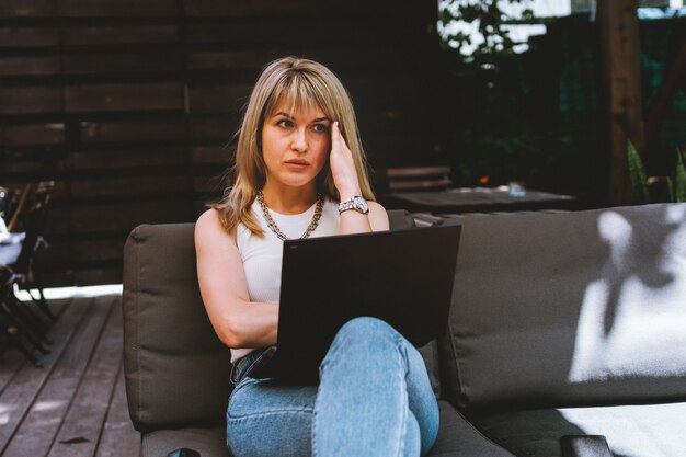 Young beautiful blondy woman working on laptop in cozy coworking space