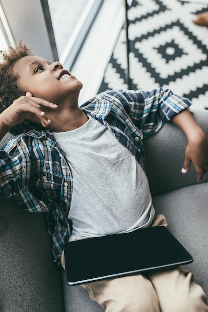 Young beautiful boy with tablet relaxing on sofa