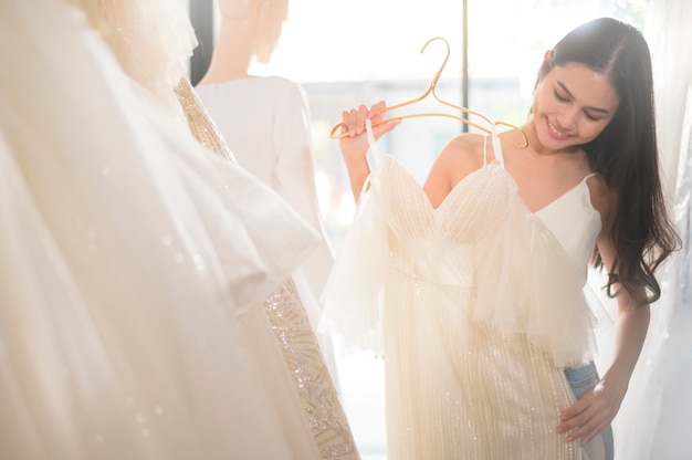 A young beautiful bride choosing a wedding outfit at wedding studio, marriage concept


