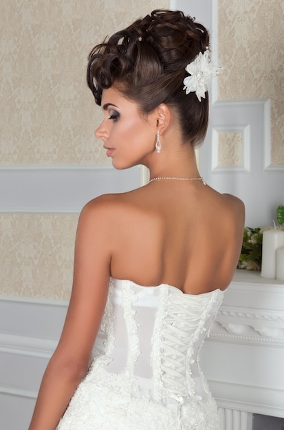 Young beautiful bride standing back to camera in white wedding dress