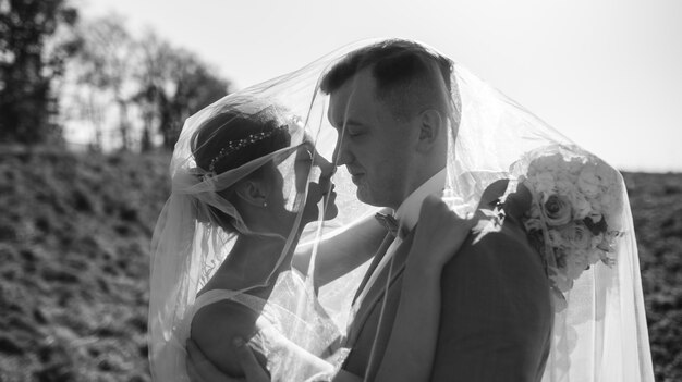 Young beautiful bride take shelter under a photo. Bright backlight shines in the frame