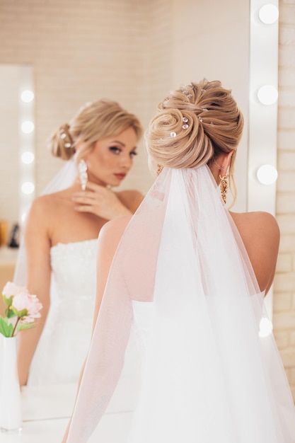 Young beautiful bride with blonde wedding hairstyle and makeup in hairdressing salon