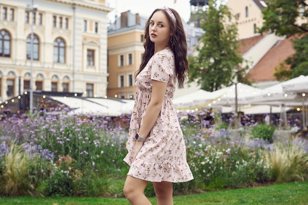 Young beautiful bright girl in a summer dress laughing in the city park