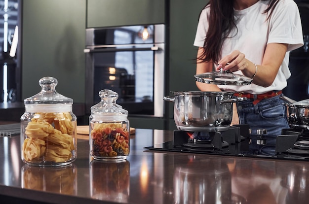 Young beautiful brunette in casual clothes preparing healthy food in kitchen at daytime