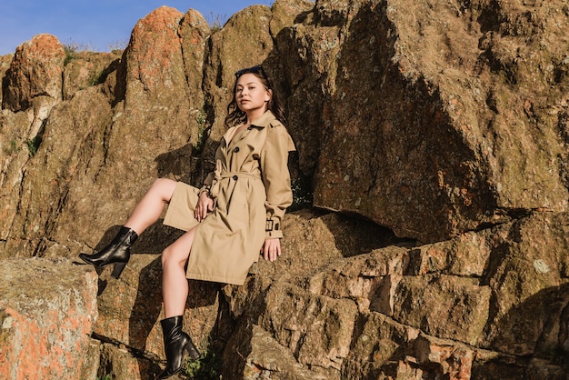 Young beautiful brunette in coat posing in nature