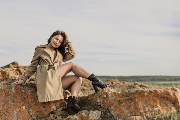 Young beautiful brunette in coat posing in nature