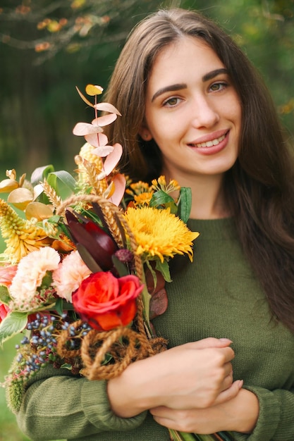 彼女の手に花を持つ若い美しいブルネットの少女